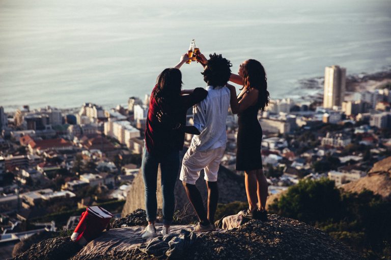 Small group of friends toasting with beer bottles on scenic view